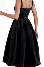 Load image into Gallery viewer, The side view of a midi black velvet dress featuring a structured bodice and corset back with lace detailing on the bust, and a pleated full volume skirt for an hourglass silhouette. Ideal for special occasions like Valentine’s Day, birthdays, date nights, black-tie events, or upscale evening wear.